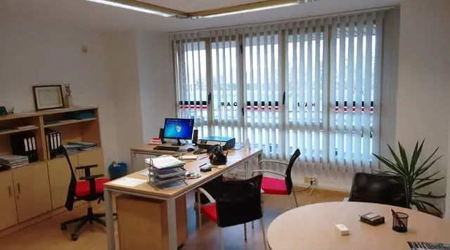 Despatx de Quatre Gestió amb taula de treball, prestatgeries i finestral